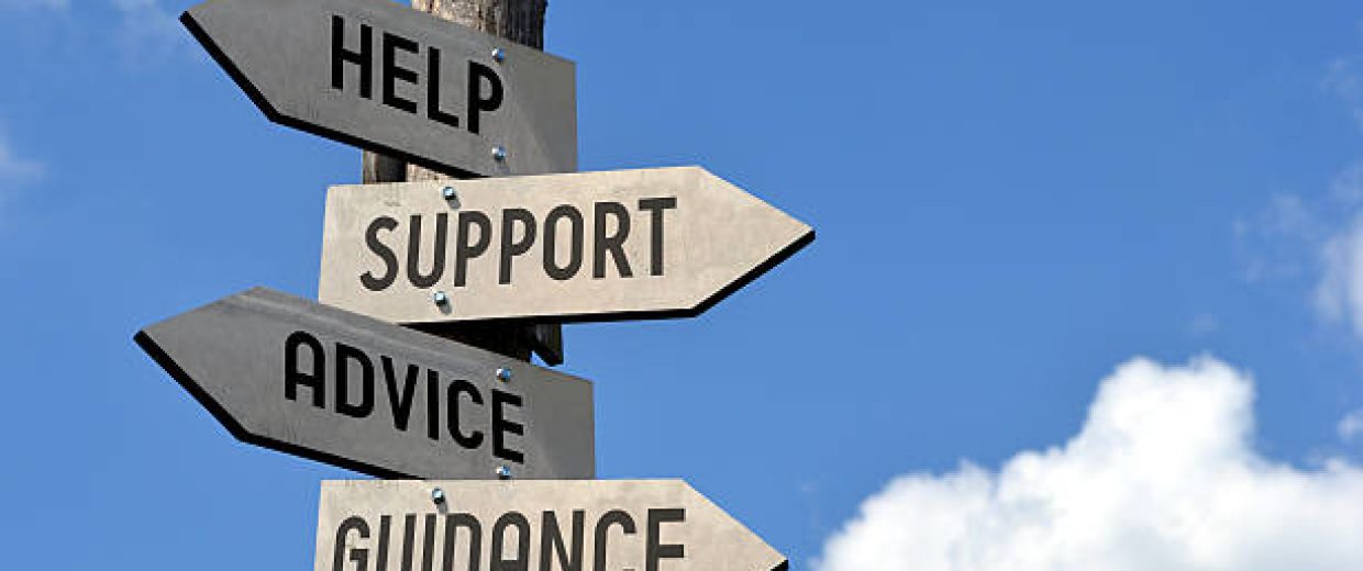 Wooden singpost with "help, support, advice, guidance" arrows against blue sky.